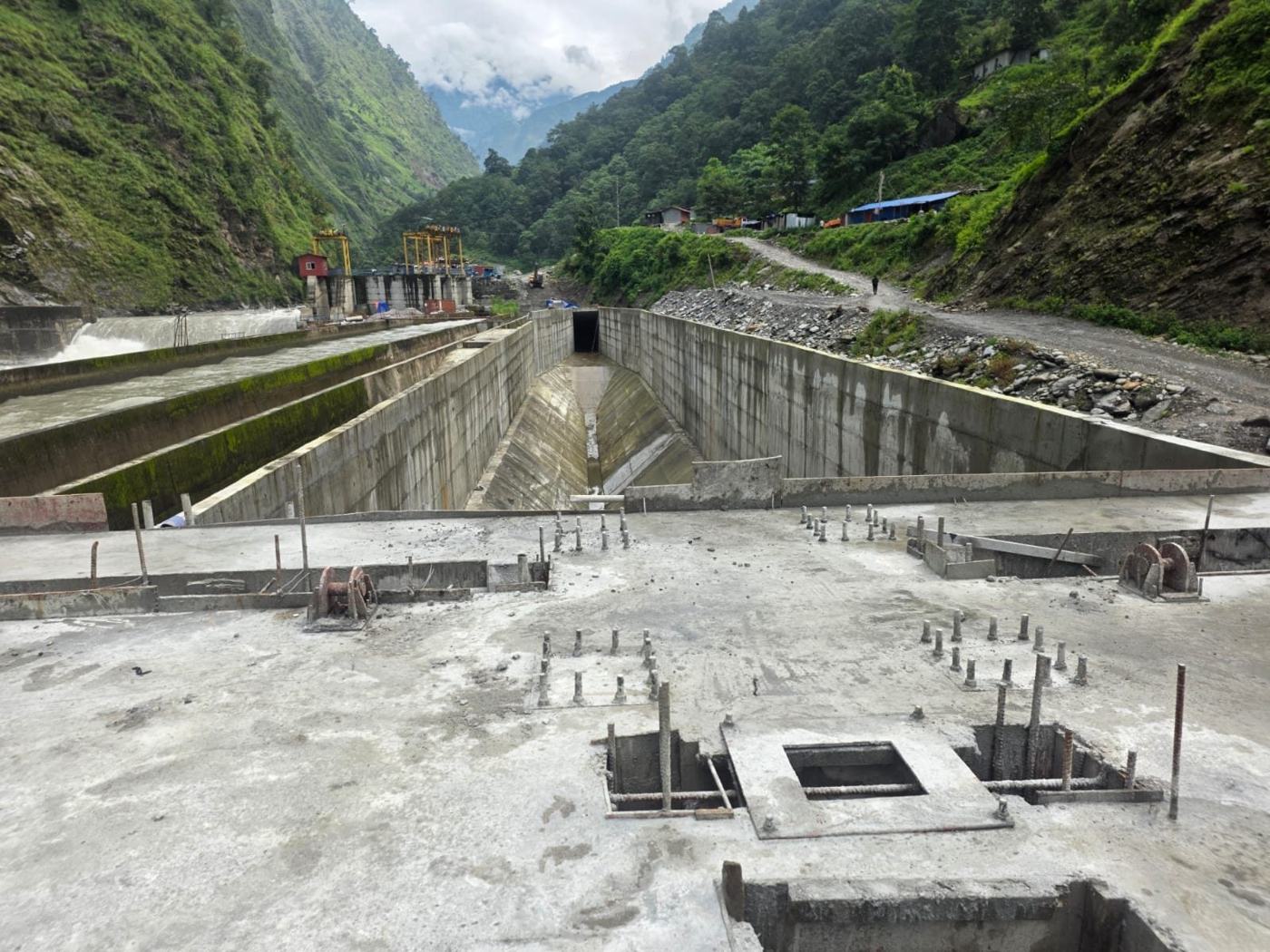 Intake channel and settling basin under rehabilitation in a forested valley